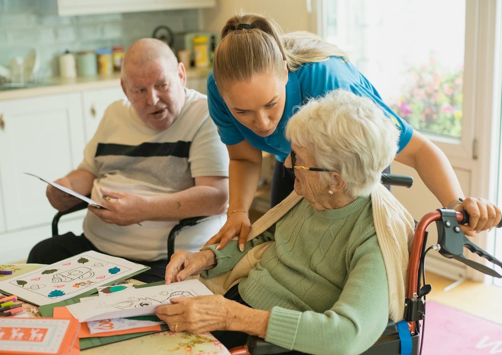A carer leaning in to help an elderly woman with an activity